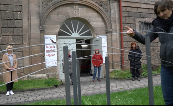 Seile werden vor der Marstall in Burgfarrnbach gespannt. Drei Frauen schauen zu.