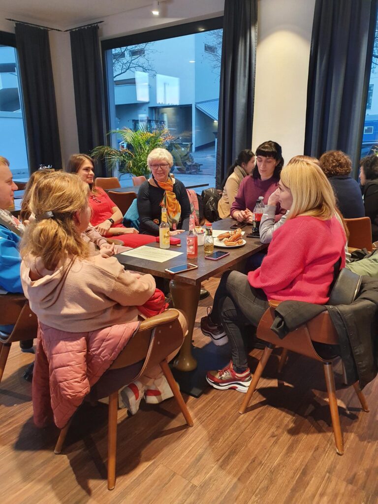 Menschen im Gespräch an einer Kaffeetafel sitzend