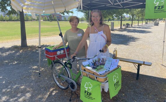 Infostand des Freiwilligenzentrums Fürth mit zwei Frauen unter dem Sonnenschirm